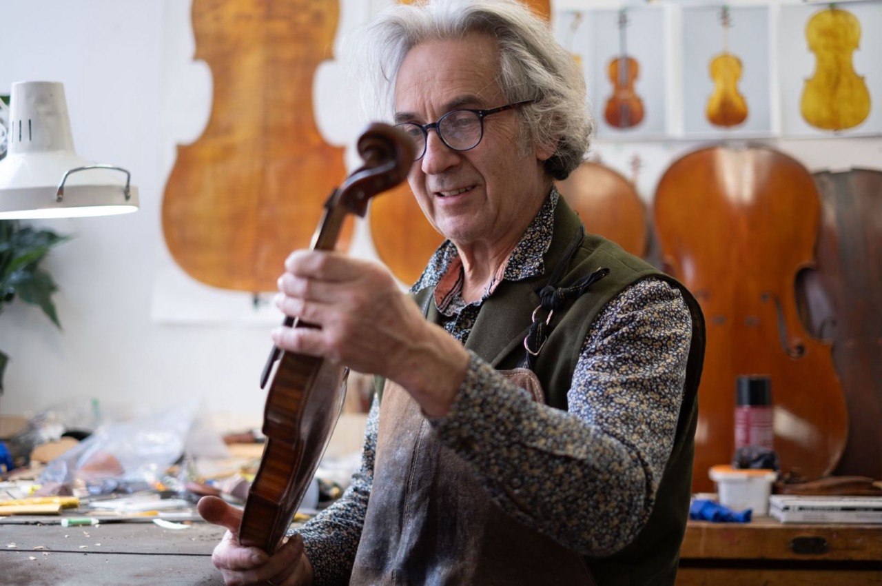 Master bowmaker Christophe Landon examining a stringed instrument in his workshop